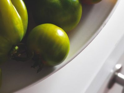 Un piatto con pomodori verdi, disposti sul top bianco di una cucina moderna.