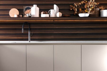 Porzione della cucina italiana di design senza maniglie E0, con una mensole in legno scuro e un piano di lavoro chiaro e pulito.