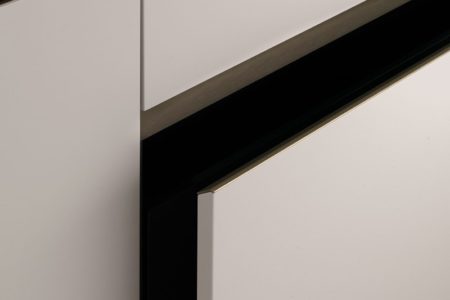 Dettaglio dell'apertura dell'anta della cucina moderna senza maniglie E0, con finiture chiare e un design elegante.