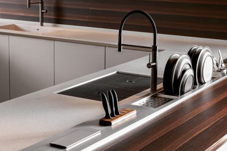 Dettaglio della cucina italiana con gola E0, con una grande isola centrale dalla superficie chiara con lavello integrato.