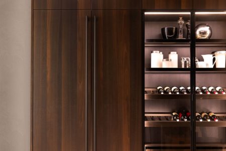 Armadio della cucina italiana di design E0 in legno scuro con ante in vetro e scaffali interni illuminati.