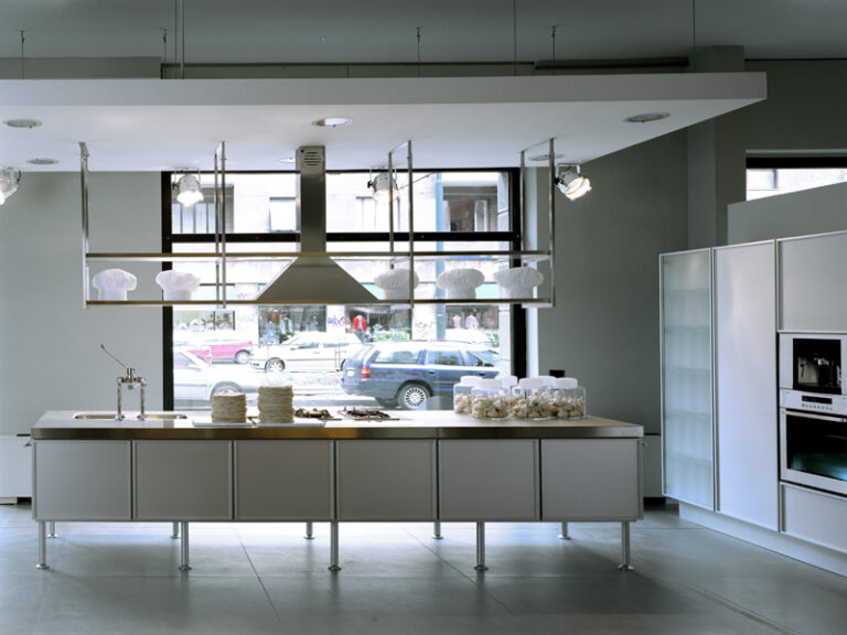 Cucina con isola senza maniglie di effeti in una pasticceria con ampie vetrate che illuminano la stanza