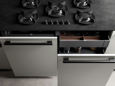 Vista da vicino della cucina di lusso E1, con focus sul piano cottura e i cassetti con maniglie ergonomiche.
