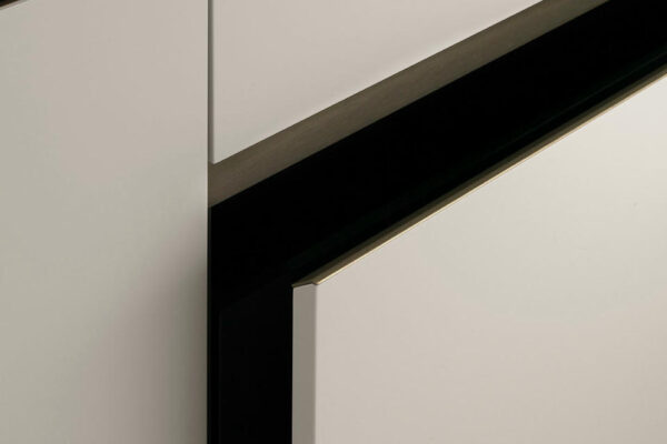 Dettaglio dell'anta senza maniglia della cucina moderna E0, dal design elegante in stile toscano, con superfici chiare e linee pulite.