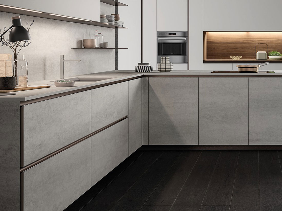 Vista della cucina senza maniglie moderna E0, con armadi e pensili in materiali chiari, e un piano di lavoro in cemento.