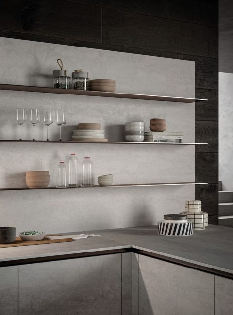 Vista della cucina con gola moderna e minimalista E0, con piani di lavoro color cemento chiaro e mensole in legno scuro.